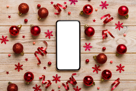 Christmas online shopping from home phone with blank white display top view. smart mobile with copy space on colored background with Christmas decorations balls,. Winter holidays sales background.の写真素材