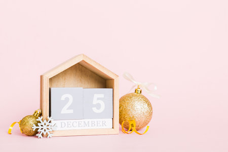 December 25th. Christmas composition on colored background with a wooden calendar, with a gift box,...