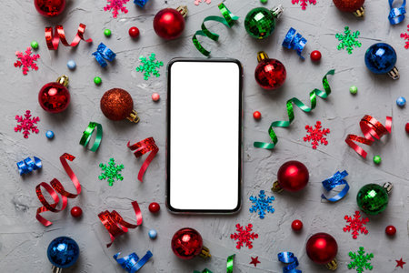 Christmas online shopping from home phone with blank white display top view. smart mobile with copy space on colored background with Christmas decorations balls,. Winter holidays sales background.の写真素材