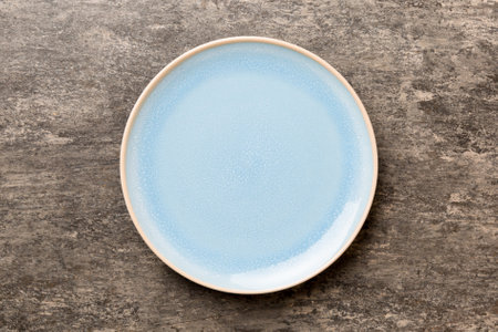 Top view of empty blue plate on cement background. Empty space for your design.
