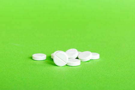 Heap of white pills on colored background. Tablets scattered on a table. Pile of red soft gelatin capsule. Vitamins and dietary supplements concept.の写真素材