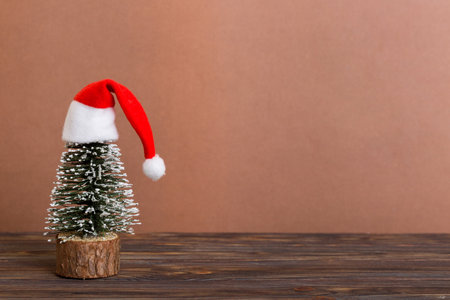One small Christmas tree with santa hat on colored background. new year decoration with copy space.の写真素材