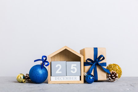 December 25th. Christmas composition on colored background with a wooden calendar, with a gift box,...