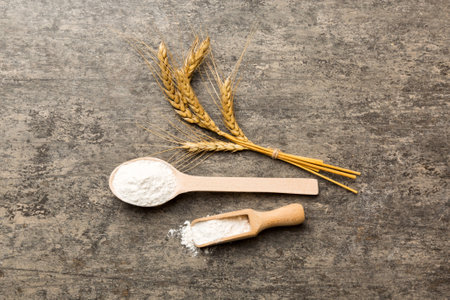 Flat lay of Wheat flour in wooden bowl with wheat spikelets on colored background. world wheat crisis.の写真素材