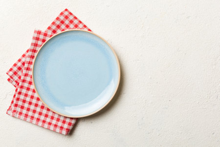 Top view on colored background empty round Blue plate on tablecloth for food. Empty dish on napkin...
