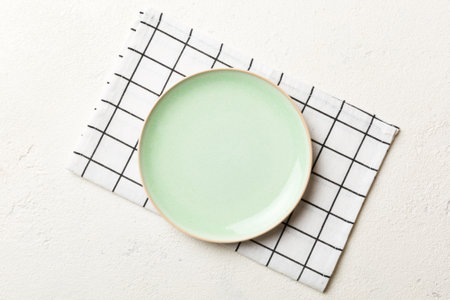 Top view on colored background empty round green plate on tablecloth for food. Empty dish on napkin with space for your design.の写真素材