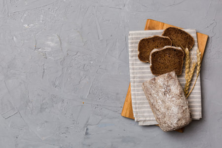 Freshly baked bread slices on cutting board against white wooden background. top view Sliced bread.