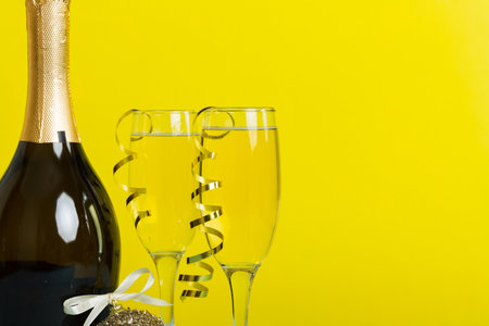 Champagne bottle with confetti, glasses and christmas decor on colored holiday background. Flat lay New Year decorations.の写真素材