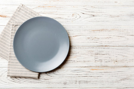 Top view on colored background empty round gray plate on tablecloth for food. Empty dish on napkin with space for your design.の写真素材