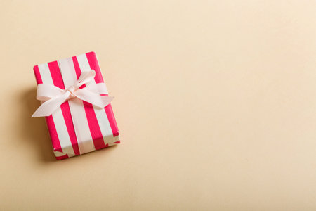 wrapped Christmas or other holiday handmade gift box in color paper with ribbon on colored background. Present box, decoration of gift on colored table, top view with copy space.の写真素材