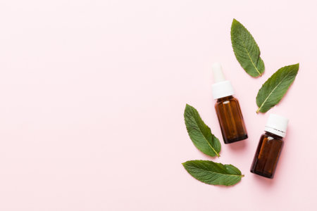 Natural Mint Essential Oil in a Glass Bottle. organic cosmetics with herbal extracts of mint on colored background.の写真素材