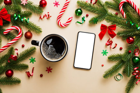 top view of smart phone with hot cup of coffee. Christmas decoration on colored background.の写真素材