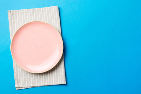 Top view on colored background empty round pink plate on tablecloth for food. Empty dish on napkin with space for your design.の写真素材