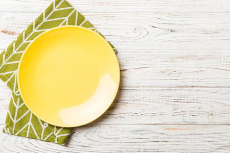 Top view on colored background empty round yellow plate on tablecloth for food. Empty dish on napkin with space for your design.の写真素材
