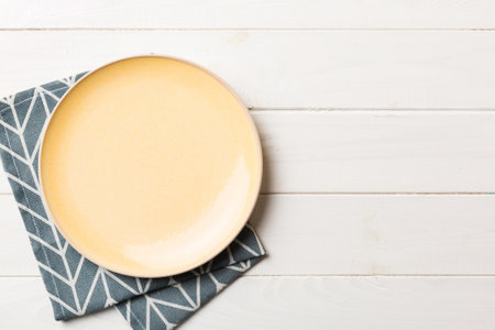 Top view on colored background empty round yellow plate on tablecloth for food. Empty dish on napkin with space for your design.の写真素材
