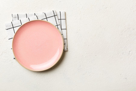 Top view on colored background empty round pink plate on tablecloth for food. Empty dish on napkin with space for your design.の写真素材