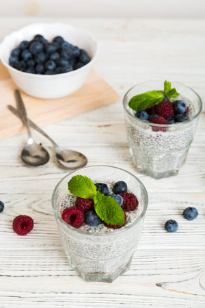 Healthy breakfast or morning with chia seeds vanilla pudding raspberry and blueberry berries on table background, vegetarian food, diet and health concept. Chia pudding with raspberry and blueberry.の写真素材