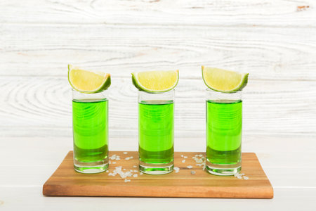Sweet refreshing mint liqueur, with ice and mint leaves on table background, Shots with lime slice and mint flat lay.の写真素材