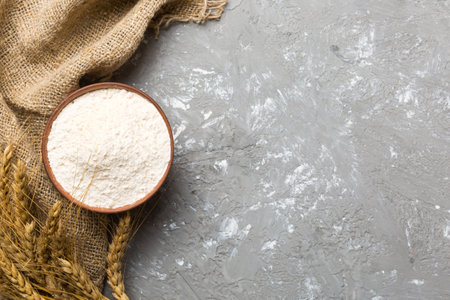 Flat lay of Wheat flour in wooden bowl with wheat spikelets on colored background. world wheat crisis.の写真素材