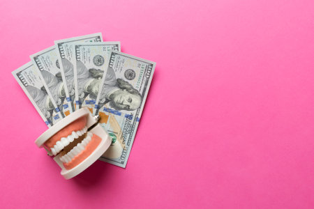 Closeup model of a human jaw with white teeth and dollar bill. Dentistry conceptual photo....