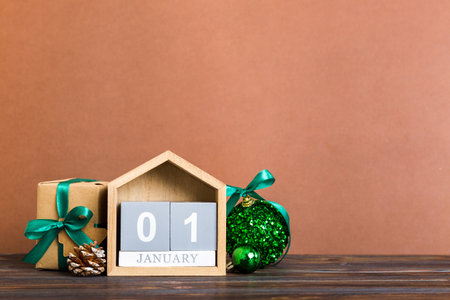 1 january. Christmas composition on colored background with a wooden calendar, with a gift box, toys, bauble copy space.の写真素材