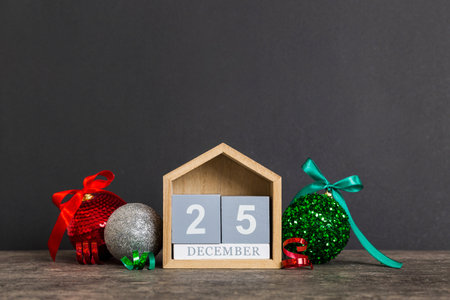 December 25th. Christmas composition on colored background with a wooden calendar, with a gift box,...