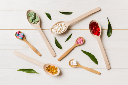 Top view Variety of vitamin and mineral pills in wooden spoon on Colored background. Top view of assorted pharmaceutical medicine pills. Dietary supplement healthcare product.の写真素材