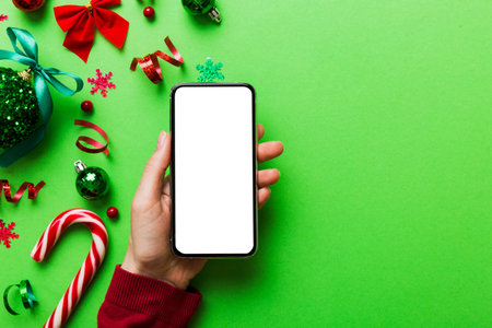 christmas mockup with space for text. christmas advertising app template. hand holding phone with empty screen on table background. Happy New Year and Xmas Flat lay.の写真素材