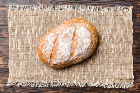 Freshly baked delicious french bread with napkin on rustic table top view. Healthy white bread loaf.