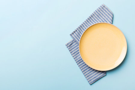 Top view on colored background empty round yellow plate on tablecloth for food. Empty dish on napkin with space for your design.の写真素材
