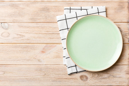 Top view on colored background empty round green plate on tablecloth for food. Empty dish on napkin with space for your design.の写真素材
