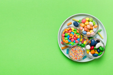 Multicolored candies in a bowl on a colored background. birthday and holiday concept. Top view with copy space.の写真素材