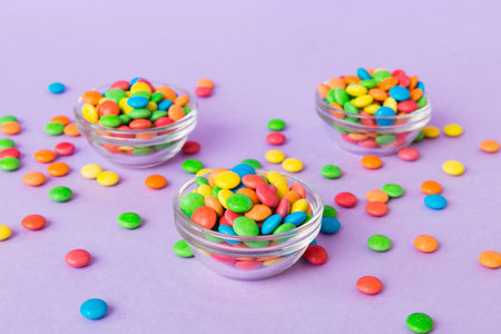 Multicolored candies in a bowl on a colored background. birthday and holiday concept. Top view with copy space.の写真素材