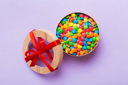 Set of different sweet candy in a paper box with a satin ribbon on a colored background. holiday...