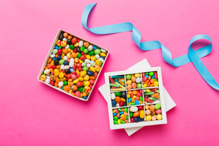 Set of different sweet candy in a paper box with a satin ribbon on a colored background. holiday concept.の写真素材