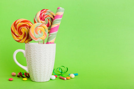 Colorful candies in cup on table on light background background. Large swirled lollipops. Creative concept of a jar full of delicious sweets from the candy store.の写真素材