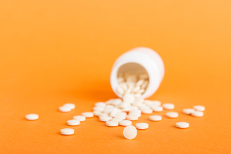 Medicine bottle and white pills spilled on a light background. Medicines and prescription pills flat...