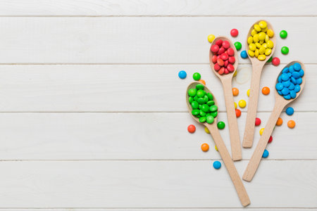 delicious colorful sweet candies on spoon on colored background . Confectionery decor top view with...