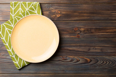 Top view on colored background empty round yellow plate on tablecloth for food. Empty dish on napkin with space for your design.の写真素材