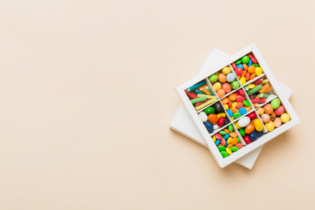 Set of different sweet candy in a paper box with a satin ribbon on a colored background. holiday concept.の写真素材