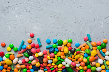Mixed collection of colorful candy, on colored background. Flat lay, top view. frame of colorful chocolate coated candy.の写真素材
