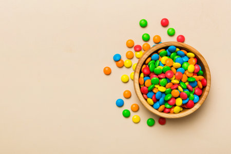 Multicolored candies in a bowl on a colored background. birthday and holiday concept. Top view with...