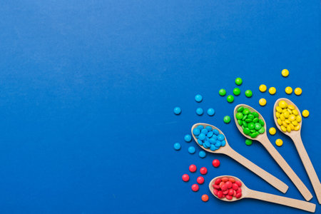 delicious colorful sweet candies on spoon on colored background . Confectionery decor top view with...