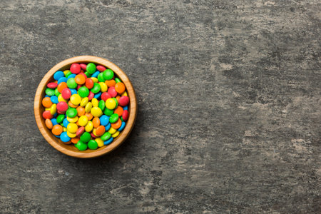 Multicolored candies in a bowl on a colored background. birthday and holiday concept. Top view with...