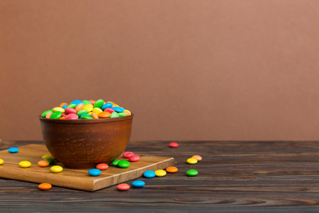 Multicolored candies in a bowl on a colored background. birthday and holiday concept. Top view with copy space.の写真素材