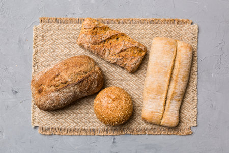 Assortment of freshly baked bread with napkin on rustic table top view. Healthy unleavened bread. French bread.の写真素材