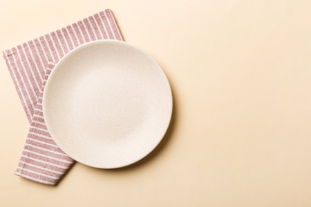 Top view on colored background empty round white plate on tablecloth for food. Empty dish on napkin with space for your design.の写真素材