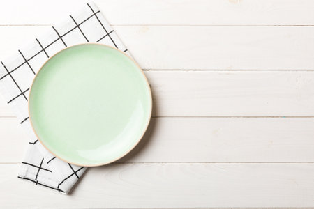 Top view on colored background empty round green plate on tablecloth for food. Empty dish on napkin with space for your design.の写真素材