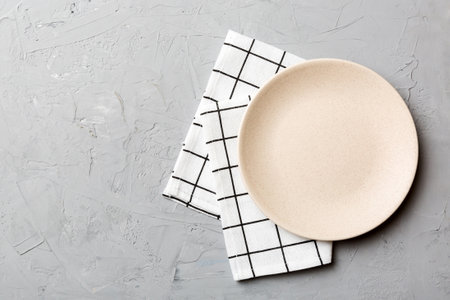 Top view on colored background empty round white plate on tablecloth for food. Empty dish on napkin...