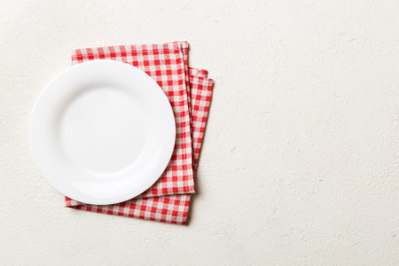 Top view on colored background empty round white plate on tablecloth for food. Empty dish on napkin with space for your design.の写真素材